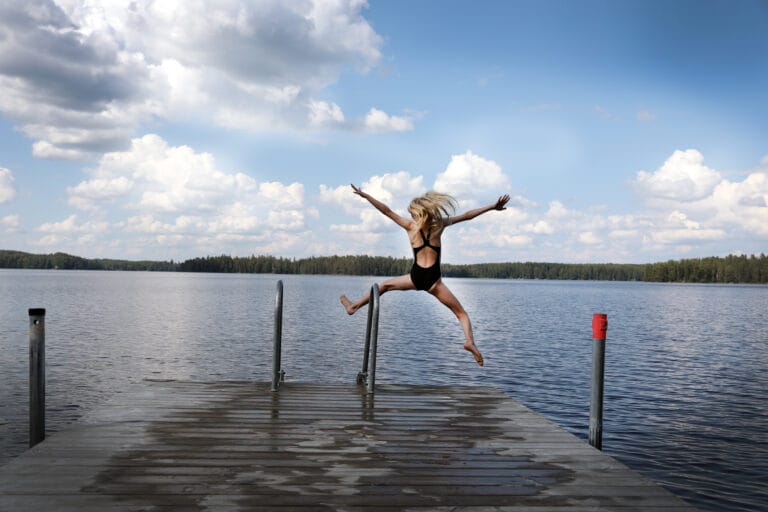 tyttö hyppää laiturilta järveen